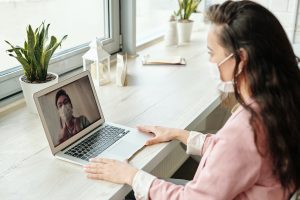 Stock image of two professionals virtual meeting wearing masks