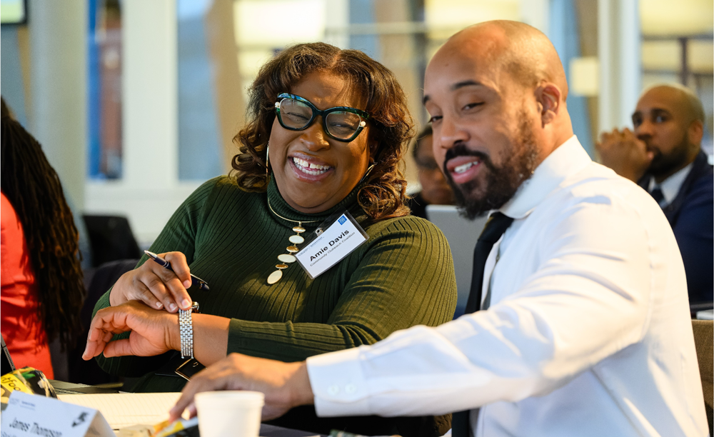 two people work on a project at a desk together and are laughing and having a great time