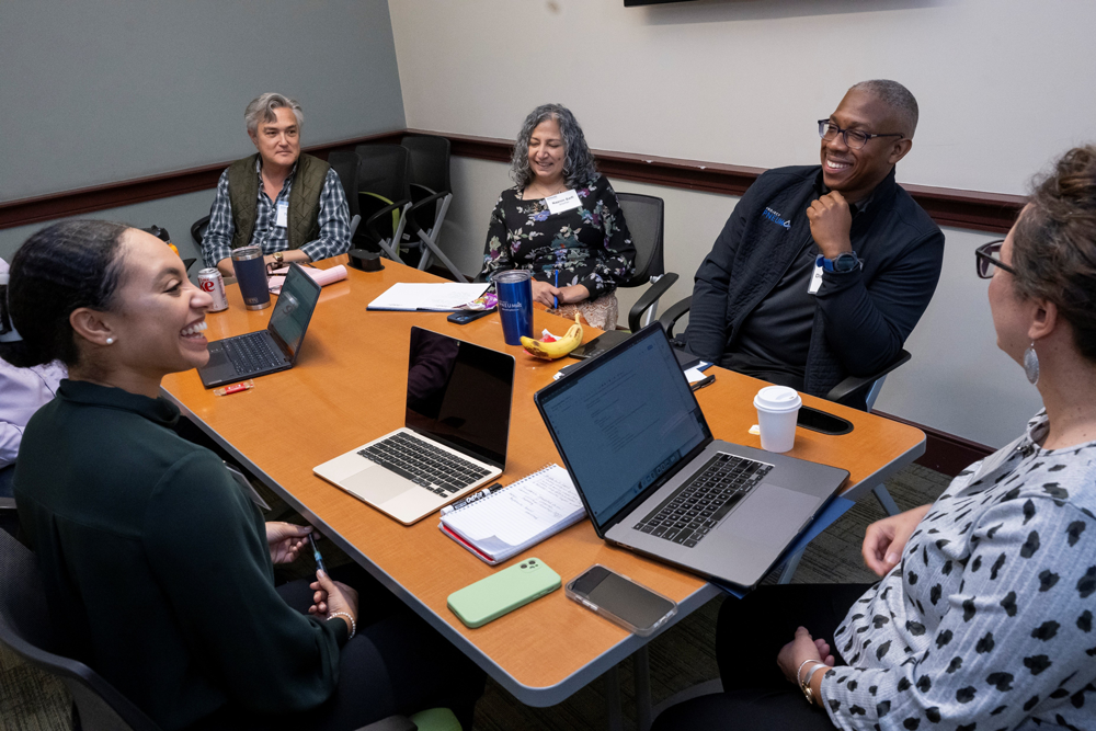 A group of people chat and laught together while working